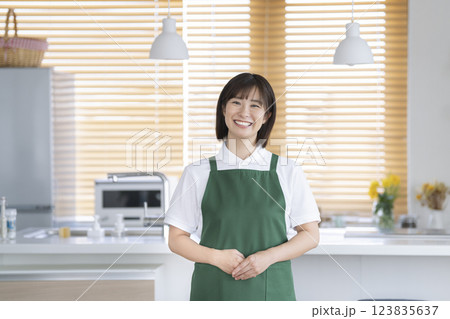 家事代行スタッフイメージ　キッチンに立つエプロンをつけた笑顔のアラサーの女性　カメラ目線 123835637