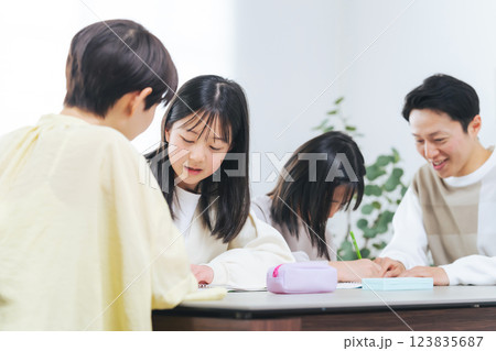 勉強する二人の女の子と指導する男女 123835687