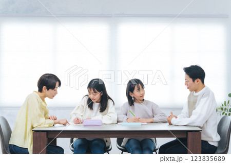 勉強する二人の女の子と指導する男女 勉強する二人の女の子と指導する男女 123835689