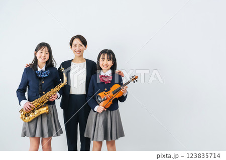 サックスとバイオリンを持った女子学生グループと女性教師 123835714