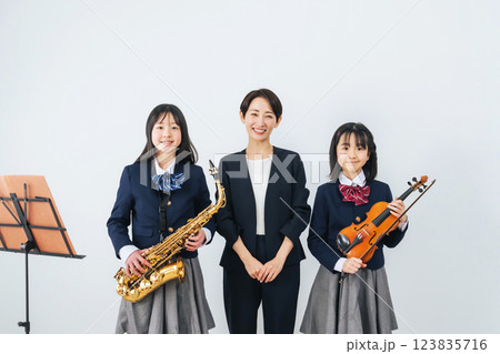 サックスとバイオリンを持った女子学生グループと女性教師 サックスとバイオリンを持った女子学生グループと女性教師 123835716