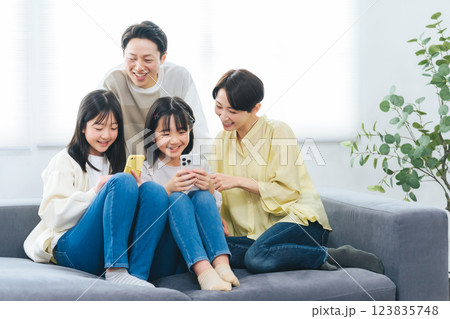 笑顔でスマホを見る小学生の女の子の家族 123835748