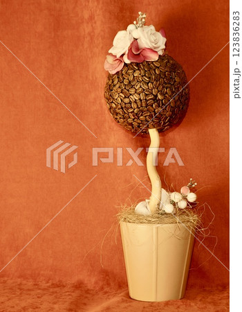 Artificial flower in the form of a ball made of coffee nuts on a red background 123836283