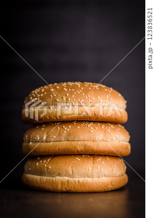 Empty burger bun with sesame seeds on black table. Empty burger bun with sesame seeds on black table. 123836521