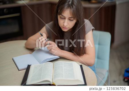 Female student learning and preparing exam at home. Woman reading textbook and taking notes Female student learning and preparing exam at home. Woman reading textbook and taking notes 123836702
