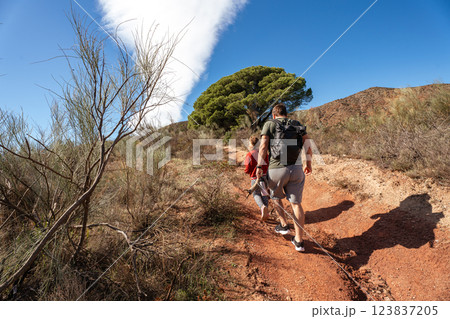 Caucasian adults and child hiking on sunny trail in nature Caucasian adults and child hiking on sunny trail in nature 123837205