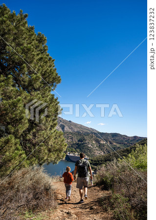 Father and son hiking on scenic mountain trail near lake, La Concepcion reservoir in Marbella Father and son hiking on scenic mountain trail near lake, La Concepcion reservoir in Marbella 123837232