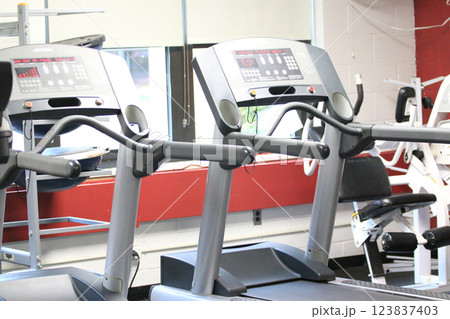 Gym Treamill Equipment Lined up in a Fitness Center During a Bright Morning Session Gym Treamill Equipment Lined up in a Fitness Center During a Bright Morning Session 123837403