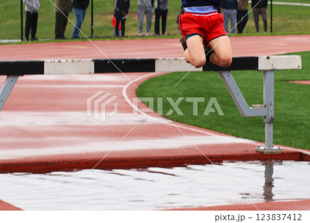 Athlete Leaps Over Steeplechase Hurdle into a Canonball Jump into the Water 123837412