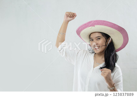 young asian girl wearing straw hat in white dress excited about holidays with waving hands, studio photo isolated on white background 123837889