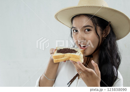 close up view of beautiful young Asian woman in straw hat and showing white bread with chocolate sprinkles smiling sweetly, isolated on white, breakfast healthy lifestyle close up view of beautiful young Asian woman in straw hat and showing white bread with chocolate sprinkles smiling sweetly, isolated on white, breakfast healthy lifestyle 123838090