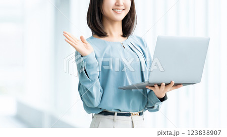 ノートパソコンを持って案内をする笑顔の女性・ビジネスウーマン 123838907