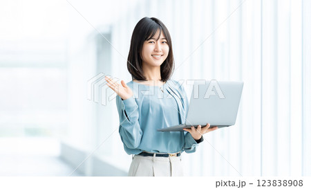 ノートパソコンを持って案内をする笑顔の女性・ビジネスウーマン 123838908