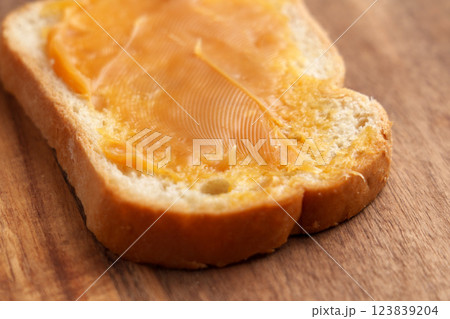 Slice of whole grain bread with smooth layer of vegan sweetened condensed coconut paste on wooden table. Healthy vegetarian snack Slice of whole grain bread with smooth layer of vegan sweetened condensed coconut paste on wooden table. Healthy vegetarian snack 123839204