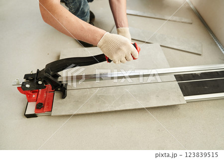 A close-up of the hands of a master who divides time into two parts using a machine. An installation for cutting large ceramic tiles into smaller ones with precise dimensions. High quality photo 123839515