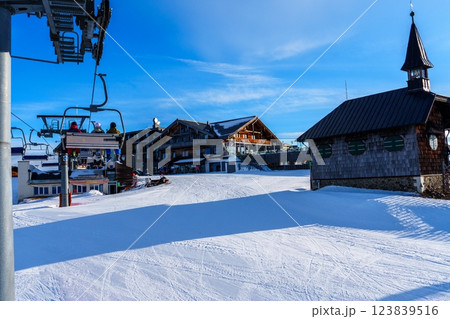 A ski resort with a chairlift, a building, and a clock tower in the background 123839516