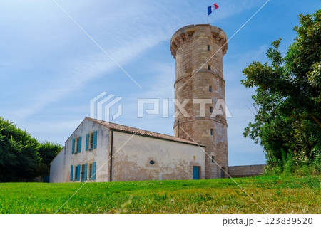 Stone watchtower with blue shutters and a French flag flying from the top 123839520