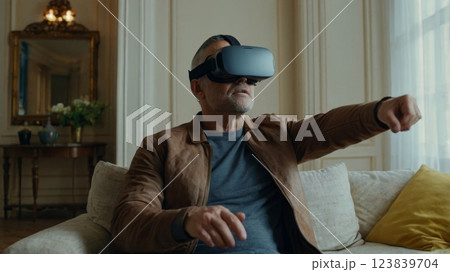 Man wearing VR virtual reality glasses playing on sofa in room 123839704