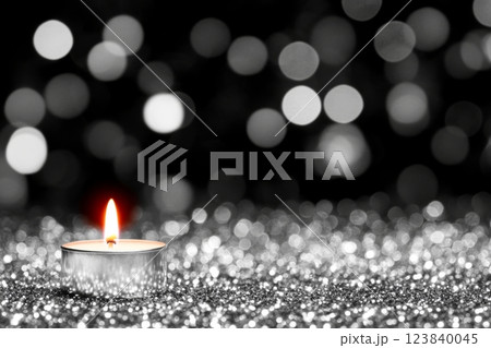 Candle illuminates a sparkling surface in soft light 123840045