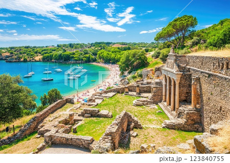 Scenic view of ancient ruins overlooking a picturesque beach with boats and clear blue waters under a bright sky 123840755