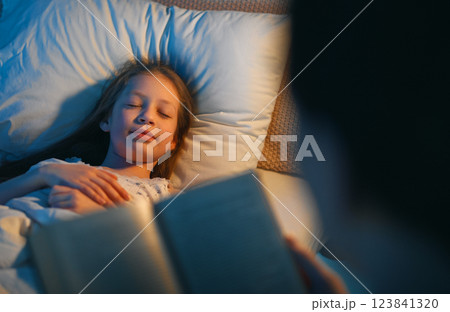 mother reading a book to her daughter mother reading a book to her daughter 123841320