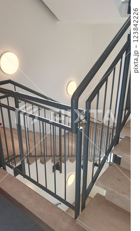 Internal staircase with marble stone beige stairs inside the building and metal railings. Internal staircase with marble stone beige stairs inside the building and metal railings. 123842226