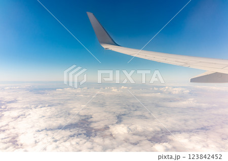 View from the airplane window at a beautiful cloudy sky and the airplane wing View from the airplane window at a beautiful cloudy sky and the airplane wing 123842452