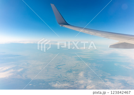 View from the airplane window at a beautiful blue clear sky, earth, sea and the airplane wing 123842467