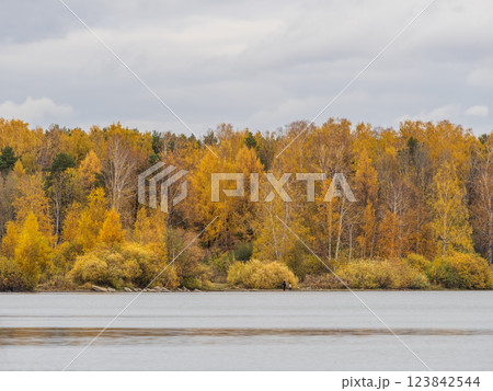 Autumn lake with trees on the shores. Reflection of blue sky with clouds in water. 123842544