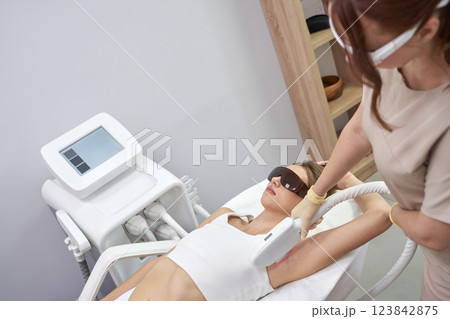 Young caucasian female receiving laser hair removal treatment in modern 123842875