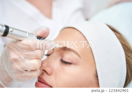 Caucasian female receiving eyebrow microblading treatment close up at beauty Caucasian female receiving eyebrow microblading treatment close up at beauty 123842901