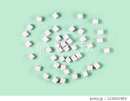 Scattered white sugar cubes on light green background in random pattern 123842964