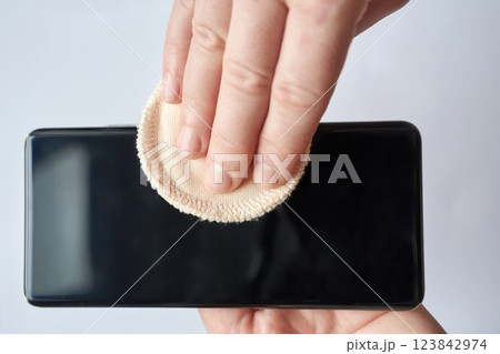 Female hands cleaning smartphone screen with cloth disc on light background 123842974
