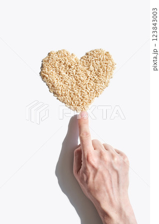 Caucasian hand touching heart shaped rice symbolizing love for healthy food Caucasian hand touching heart shaped rice symbolizing love for healthy food 123843003