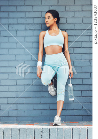 Fitness, fit and exercise with woman out for a run, running and cardio workout in city against brick wall. Health, wellness and athlete female ready for sports training with water bottle for running 123843037