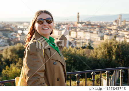 Young female tourist pointing something and resting in Italy. Florence city landscape panoramic view. Stylish woman visiting Italian landmarks. Traveling Europe, Italy in spring Young female tourist pointing something and resting in Italy. Florence city landscape panoramic view. Stylish woman visiting Italian landmarks. Traveling Europe, Italy in spring 123843748
