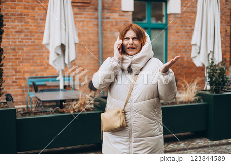 Angry woman on cell phone walking outside building. Frustrated woman talking on phone. Autumn time. Negative people emotion 123844589