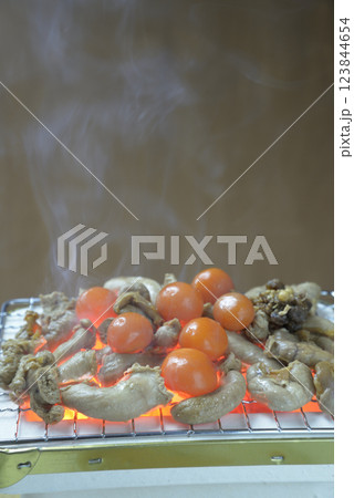 煙り立ち昇る七輪で鶏モツを焼く 123844654