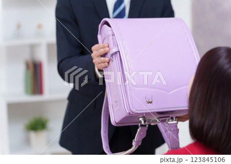子供に入学祝いのランドセルをプレゼントする親 123845106
