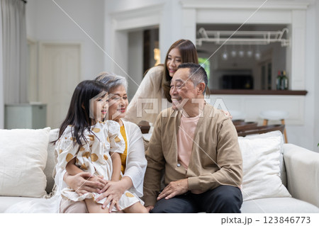 Family is spending joyful moments in comfortable living room, with three generations present. grandparents are smiling at their granddaughter, while the mother enjoys the warm atmosphere. Family is spending joyful moments in comfortable living room, with three generations present. grandparents are smiling at their granddaughter, while the mother enjoys the warm atmosphere. 123846773