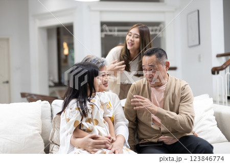Family is spending joyful moments in comfortable living room, with three generations present. grandparents are smiling at their granddaughter, while the mother enjoys the warm atmosphere. Family is spending joyful moments in comfortable living room, with three generations present. grandparents are smiling at their granddaughter, while the mother enjoys the warm atmosphere. 123846774