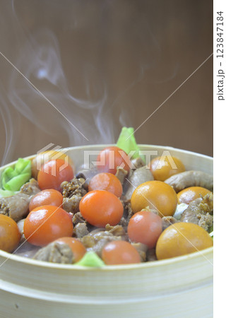 湯気の立ち昇る蒸籠で鶏モツを蒸す 123847184