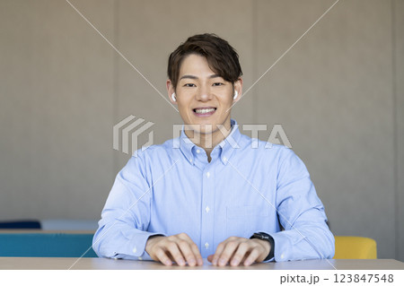 カメラ目線で話すイヤホンをつけた30代の男性 123847548