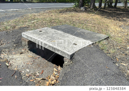 An old concrete water drain located near a road 123848384