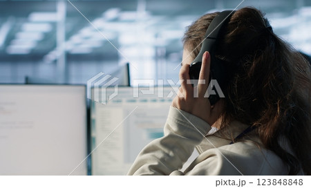 Engineer typing on computer in server hub, checking recovery plan, monitoring data center energy consumption, listening music. Technician wearing headphones inspecting rackmounts, camera A close up Engineer typing on computer in server hub, checking recovery plan, monitoring data center energy consumption, listening music. Technician wearing headphones inspecting rackmounts, camera A close up 123848848