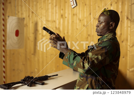 Man reloading firearm in shooting range used to train and test soldiers on necessary combat skills. Army soldier loading ammo magazine in pistol, training to enhance combat readiness 123848979