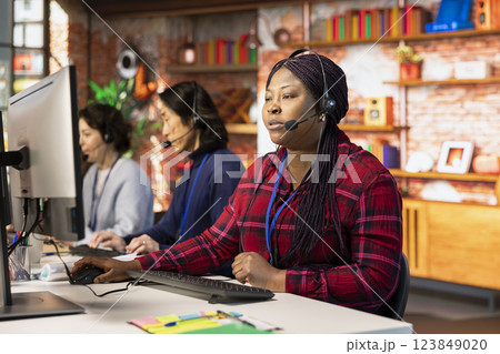 Teamworking call center colleagues in office helping customers by answering questions. Team of agents in customer support workplace in front of PC using headset mic to talk with clients Teamworking call center colleagues in office helping customers by answering questions. Team of agents in customer support workplace in front of PC using headset mic to talk with clients 123849020