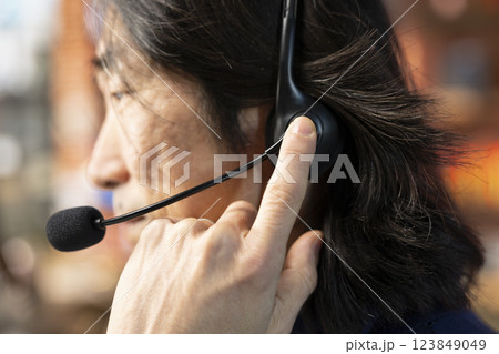 Call center staff member using headphones mic to answer technical inquiries about hardware issues. Knowledgeable Asian worker doing customer support job using PC to troubleshoot problems, close up 123849049