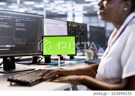 Programmer using green screen tablet to check for signs of failure in data center supercomputers. Woman working on mockup device to prevent damages in server farm, monitoring systems Programmer using green screen tablet to check for signs of failure in data center supercomputers. Woman working on mockup device to prevent damages in server farm, monitoring systems 123849135