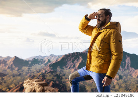 Hiker gazes at the panoramic view of dramatic mountain peaks and clouds, feeling the thrill of adventure and rewards of perseverance. The journey represents strength and personal growth. 123849180